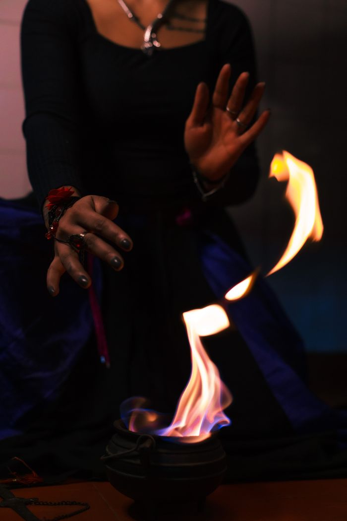 services-01 An enchanting scene of a witchcraft ritual with hands casting flames above a cauldron, creating a mystical atmosphere.
