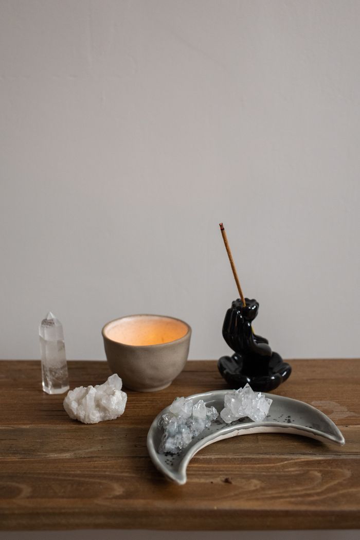 services-02 Calming setup with crystals, a lit candle, and incense on a wooden table.